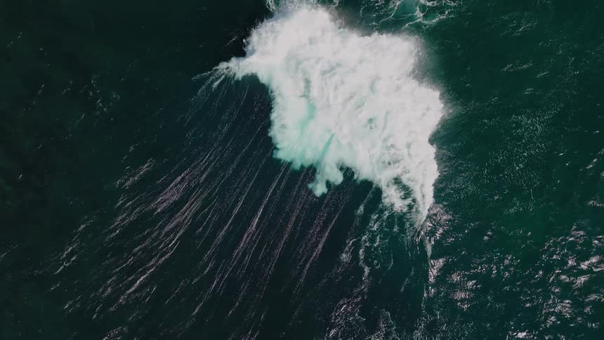 The large wave crashes in the ocean