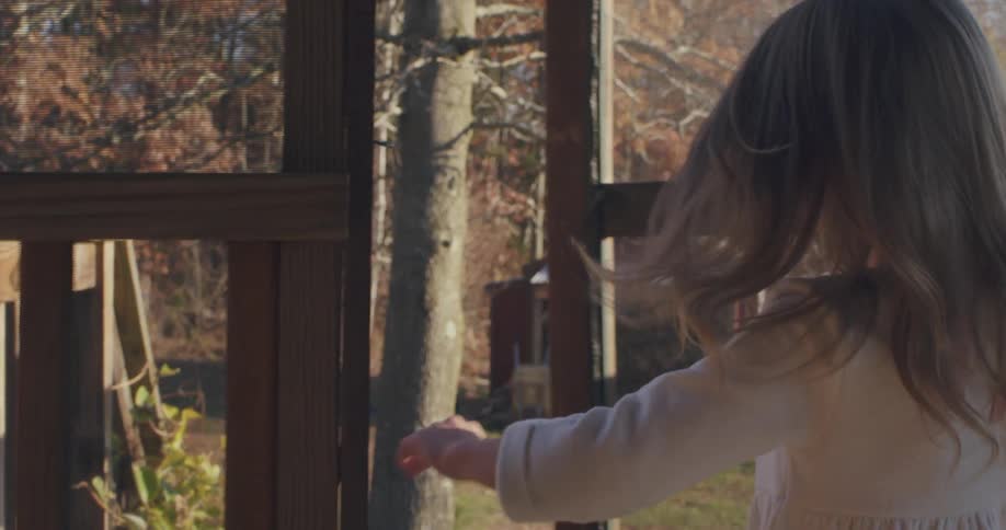 A girl runs towards a door opening it into a yard