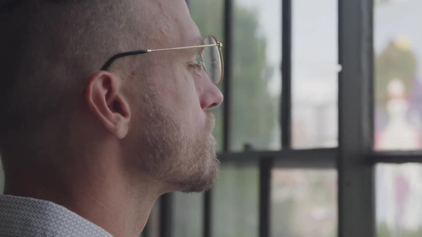 While thinking to himself a man stares out a window