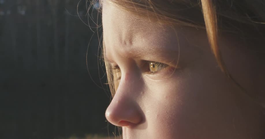 A girl looks forward with light on her face