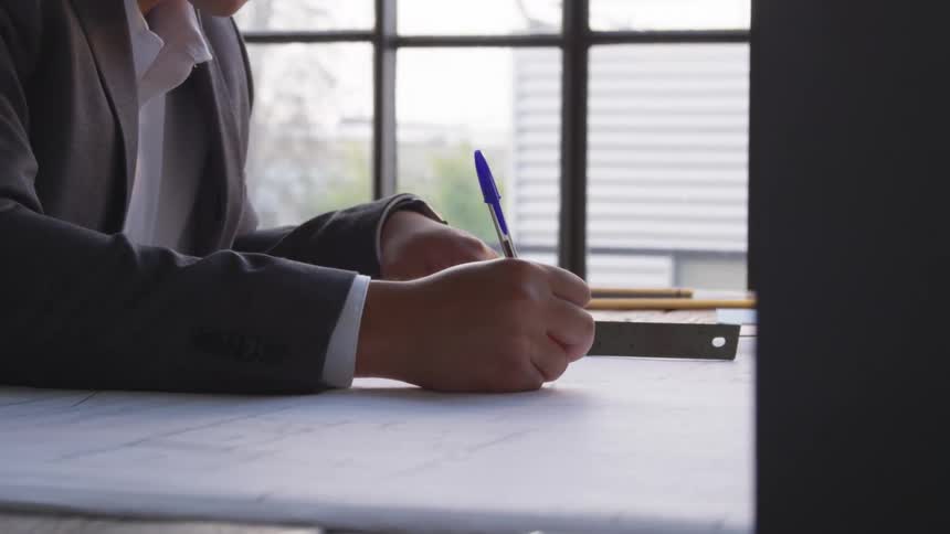 A man is writing in the office with a pen