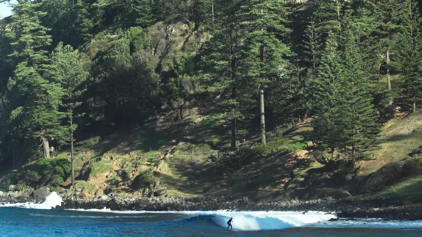 A surfer cuts through a small wave