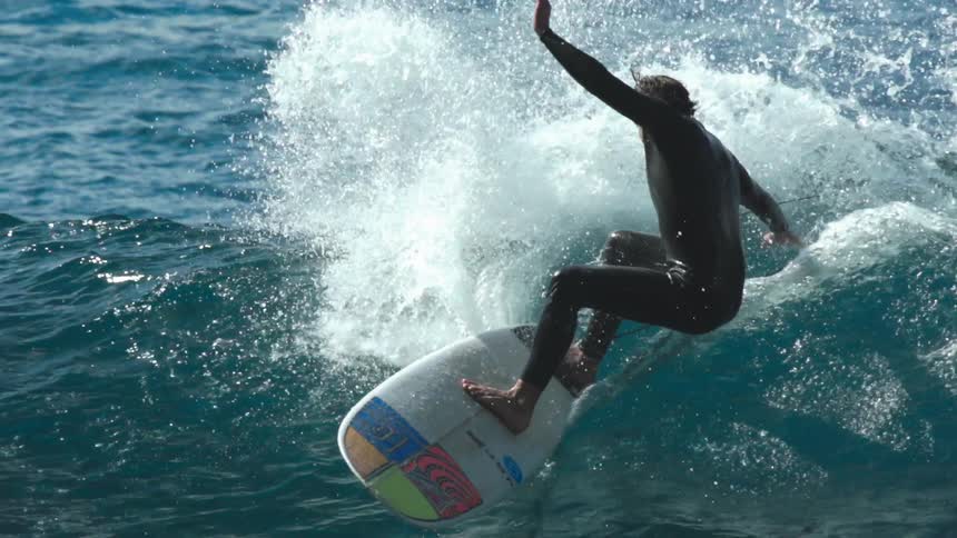 A man is surfing through big waves in the ocean water