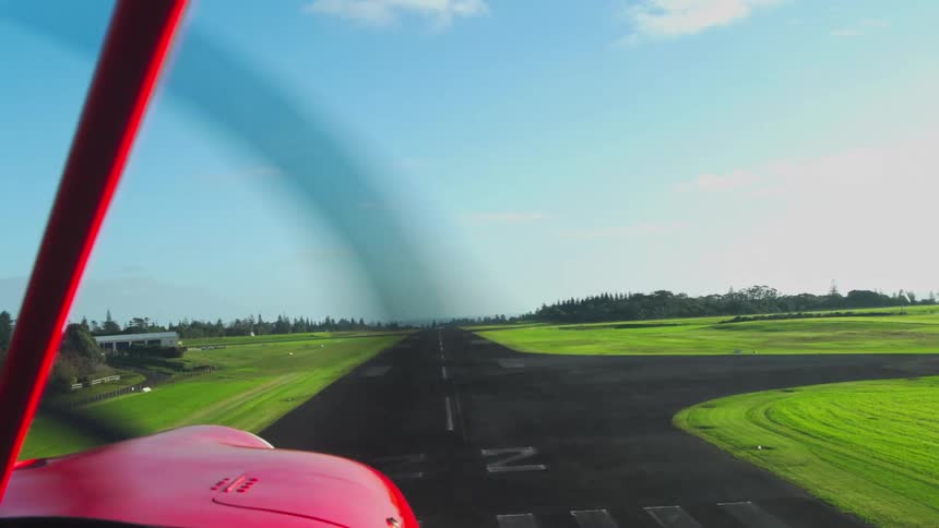 Red airplane lands on a runway in the rural countryside on a summer day