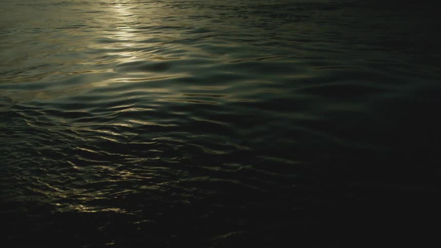 Ripples in the ocean as the sun sets in the distance