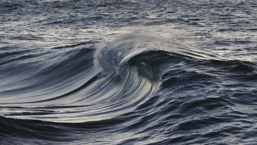 Large wave swells and crests spraying water through the air