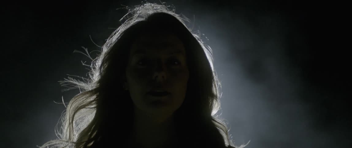 Woman's head moving in front of a bright light behind her leaving only the silhouette of her head and hair