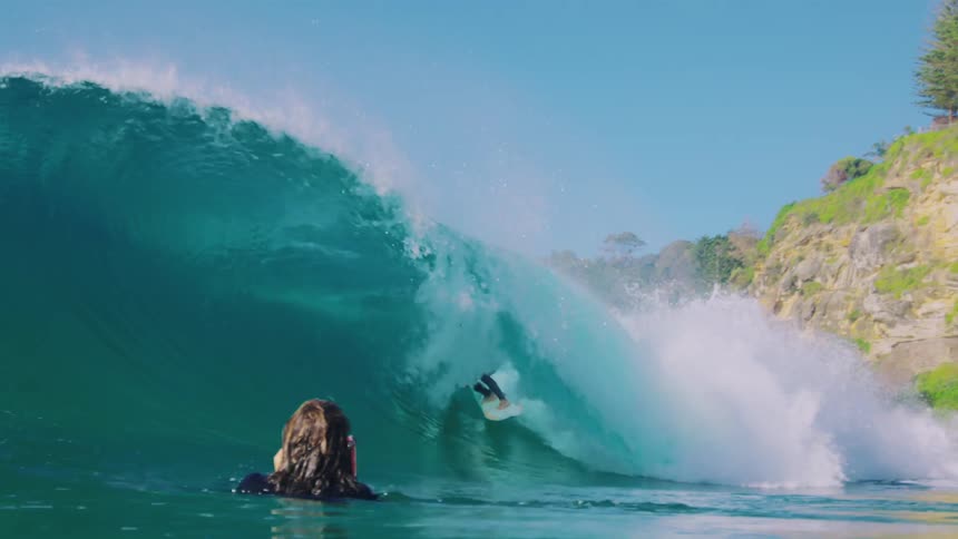 A man is being filmed surfing a wave