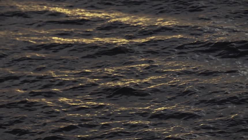 Sunlight reflections in ocean waves at sunset
