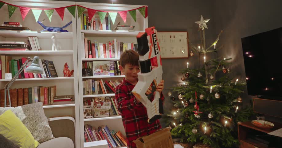 A footage of a kid playing with a toy gun indoor