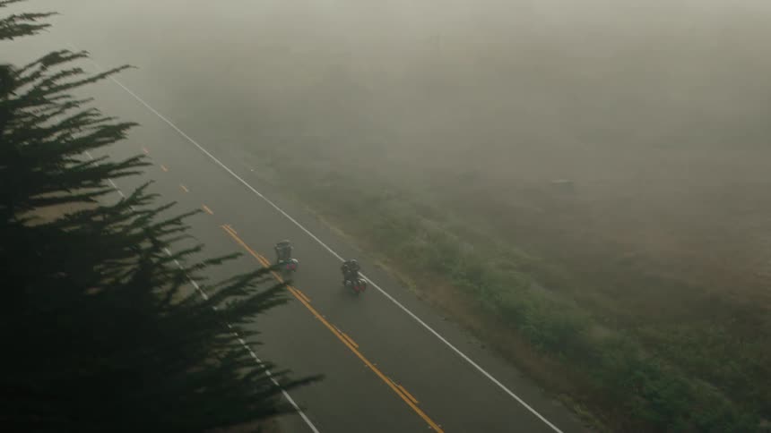 2 motorcyclists crossing a road in fog