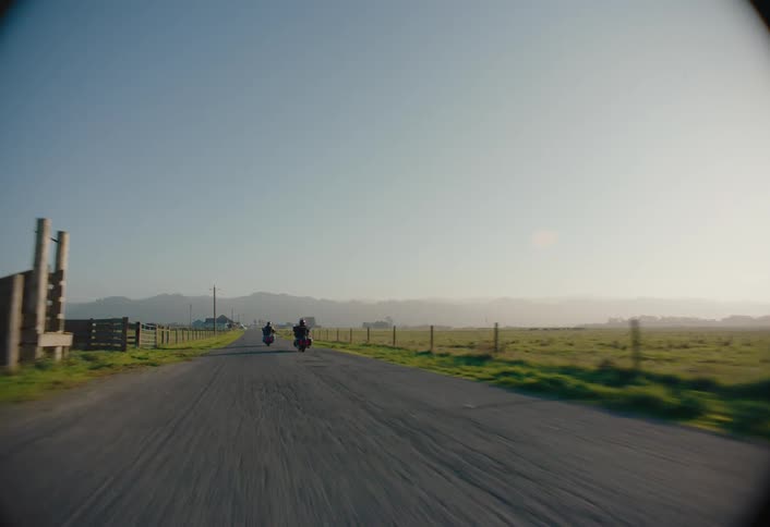 Motorcycles pass by the long fields