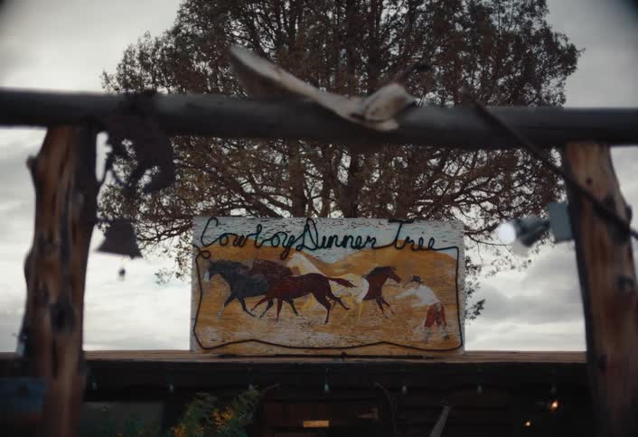 A tree is behind the sign for the ranch