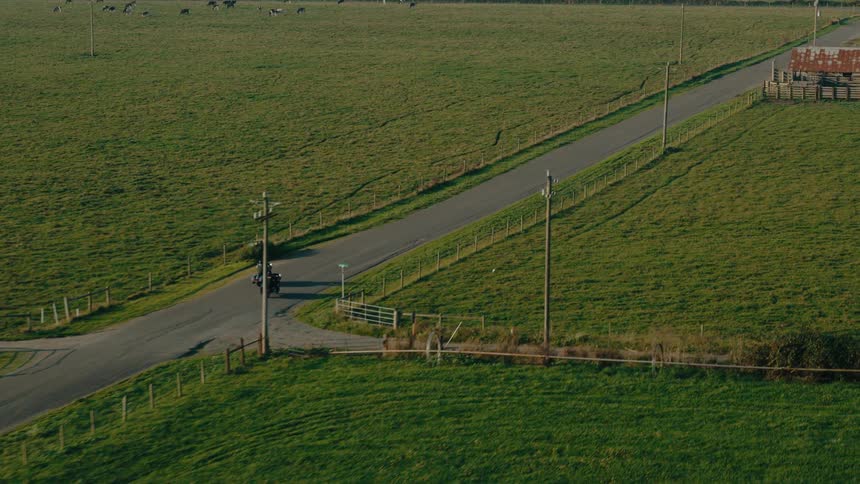 People on motorcycles drive past the farms