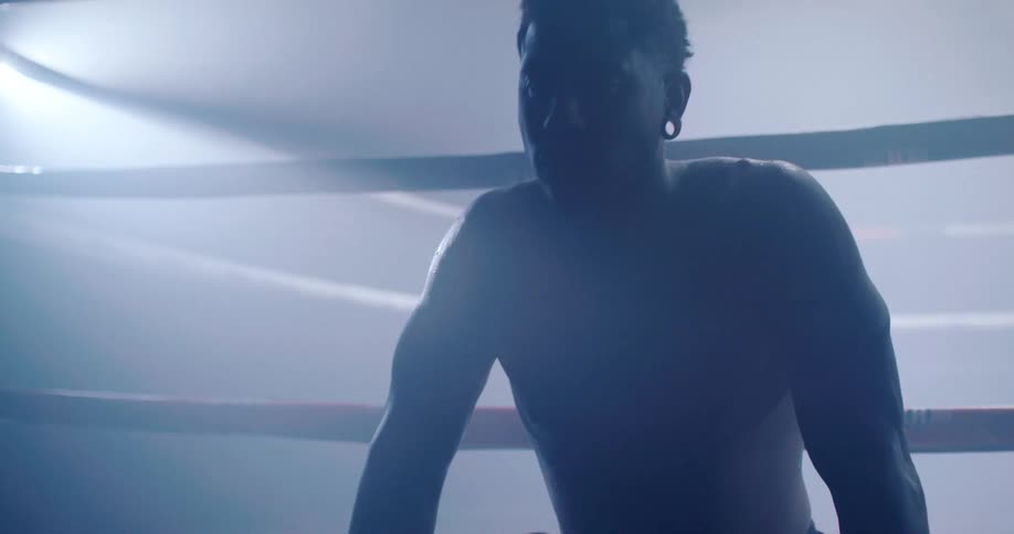 A man is resting on the boxing ring
