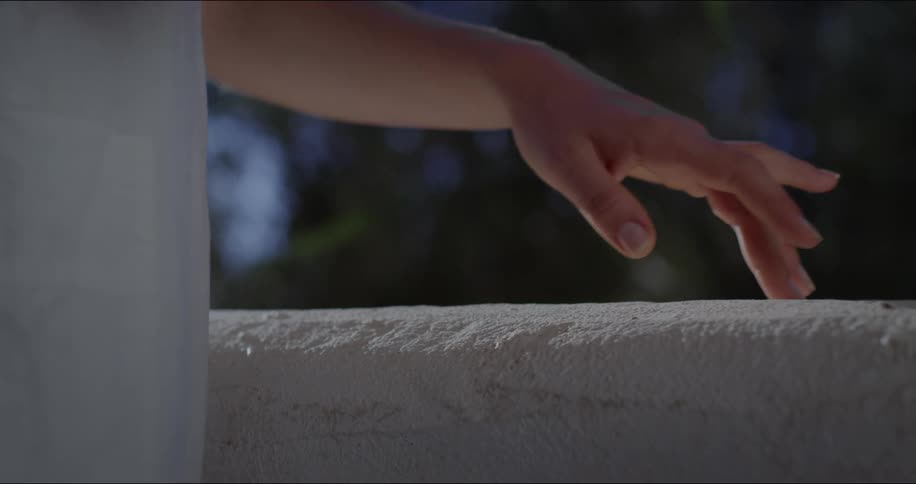 A person is touching the side of an outdoor fence