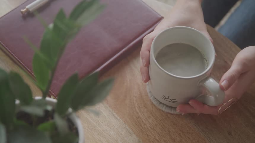 A woman picks up her cup of coffee