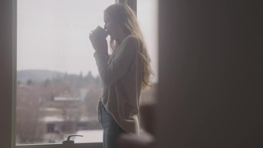 A woman is drinking coffee at home