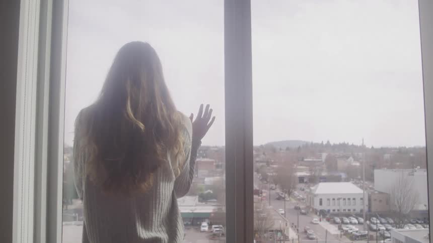 A woman is leaning against the window