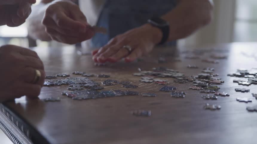 Couple building a puzzle on brown dining table