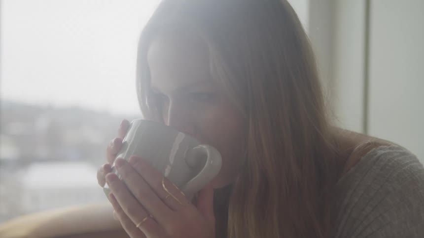A woman drinks from a mug