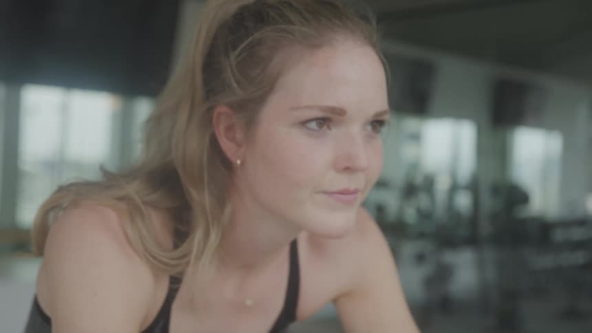 Inside a gym a woman is exercising on a stationary bike