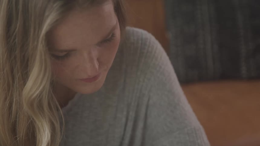 A sadlooking young woman looks down at something