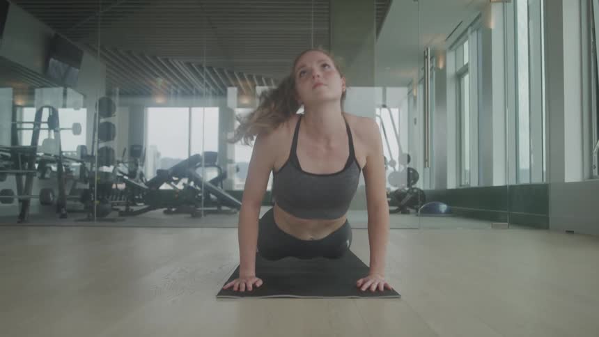 Woman doing yoga on a black yoga mat at the gym