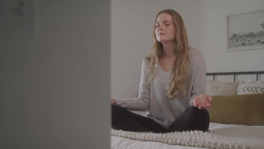 Girl sitting on bed doing meditation