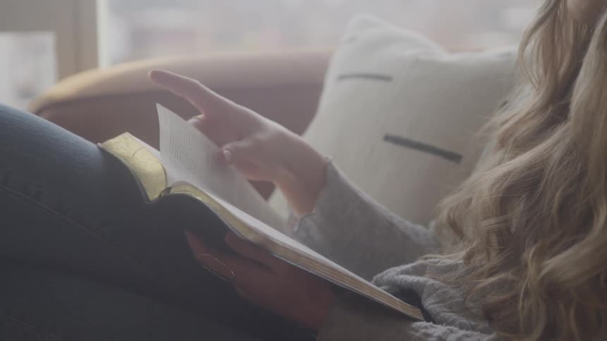 A woman flips the page of the book she is reading