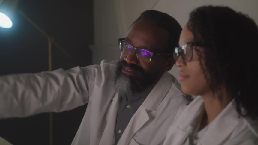 A man and woman are talking and pointing at a computer