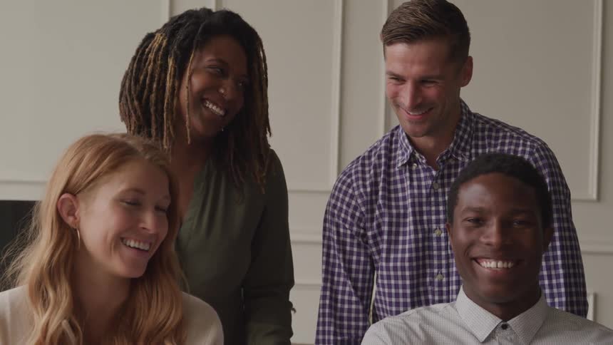 Two men and two women smile together while standing in a room