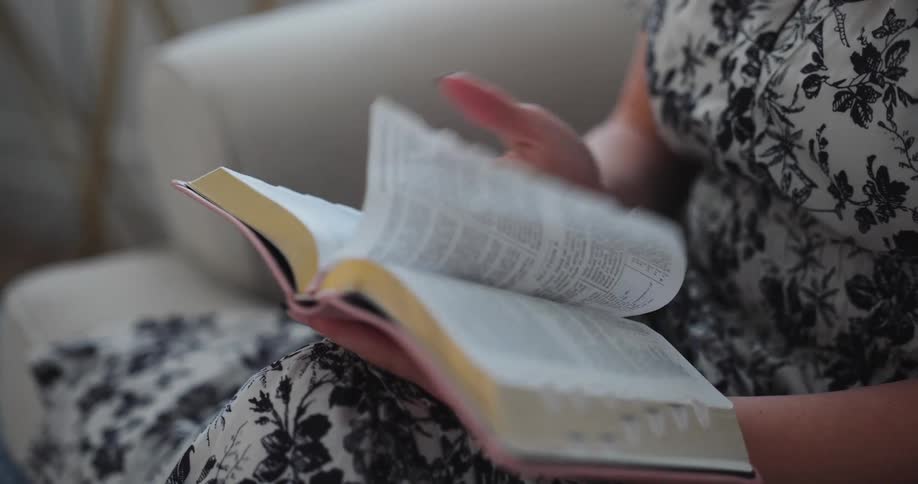 A woman flips pages while reading a book