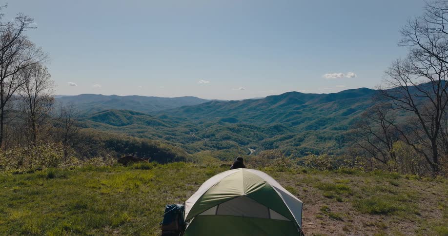 A man and woman exit the tent and hug while looking at the landscape