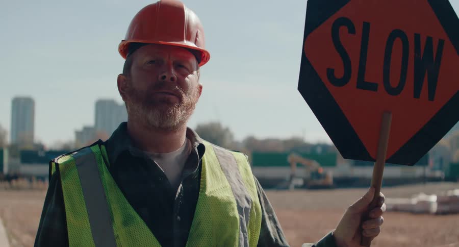 The worker flips the sign to slow in front of the train