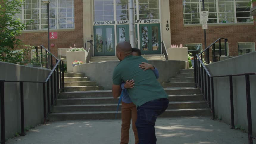 A man walks his son to the school steps and hugs him