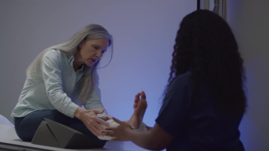 A doctor wraps a brace around the womans foot