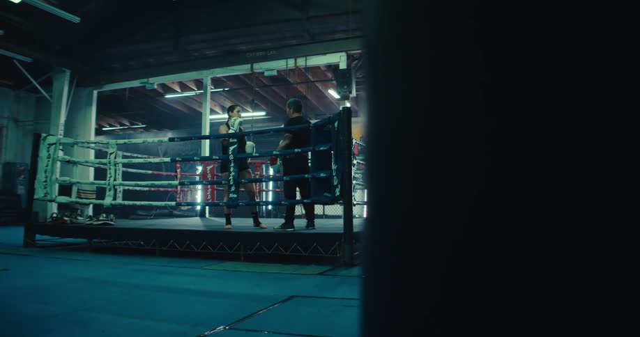 A boxer is talking with her coach in the ring