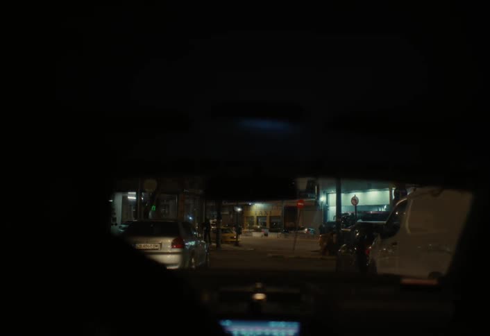 A car pulls into the parking lot at night