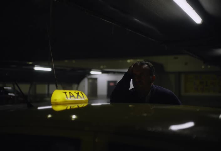 A footage of a man standing beside a taxi car