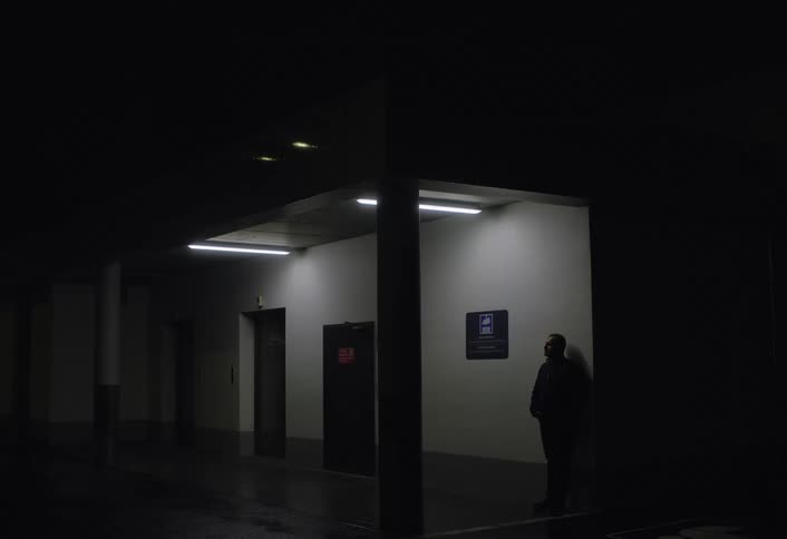Man standing under a fluorescent light in a dark room