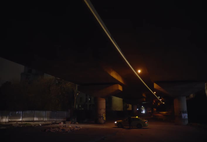 Taxi driver has car trouble while under a raised highway near downtown at night