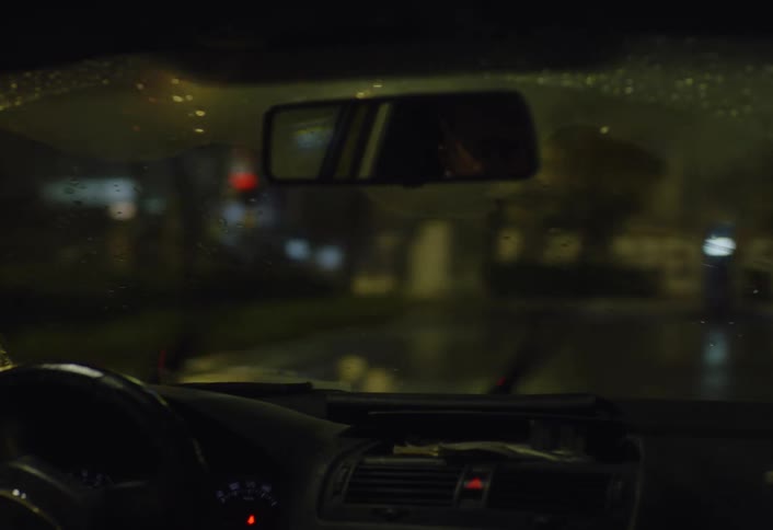 A man makes many turns in his car as it rains