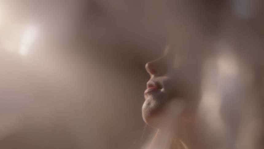A woman slowly closes her eyes looking up