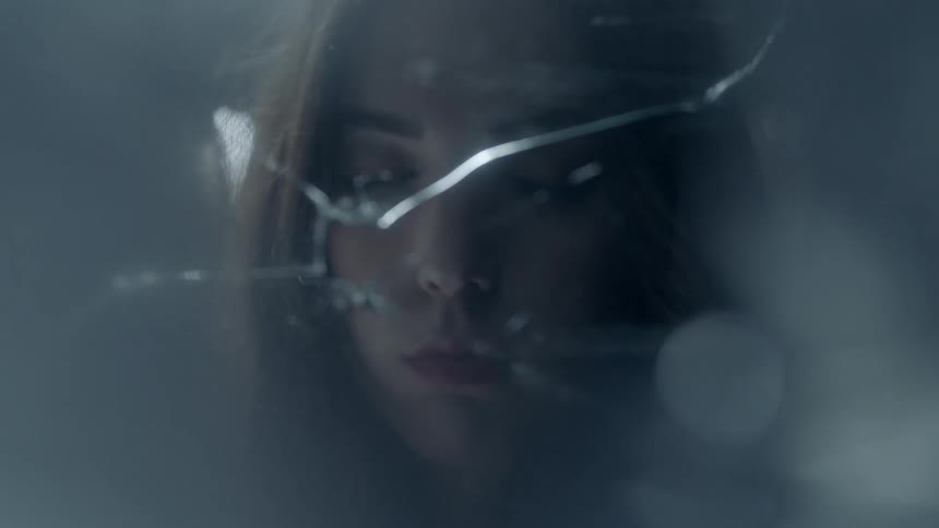 A woman is looking into a broken glass pane
