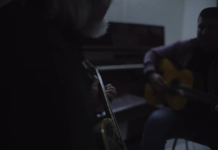 Two men are playing the guitar together