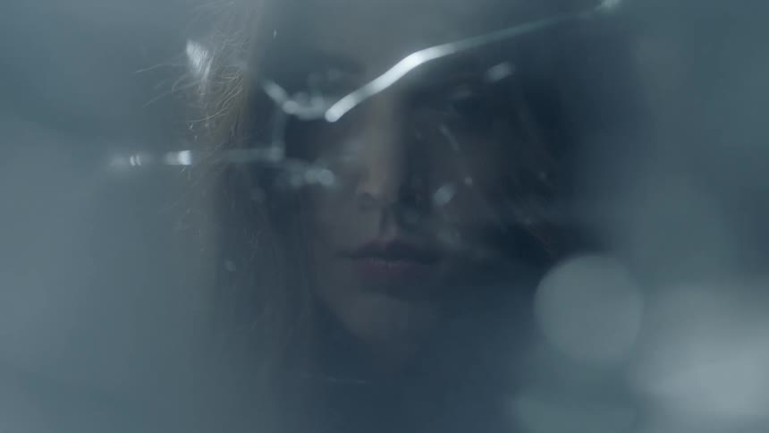 A woman is raising her head and looking into a broken mirror