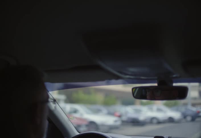 An interior view from inside a car shows blurred cars ahead on the street through the windshield