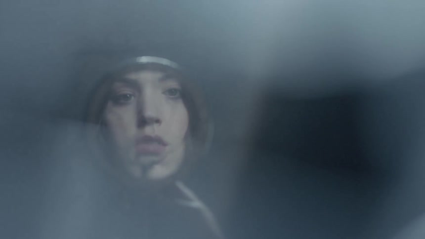 A woman looks at her reflection in a cracked hand mirror