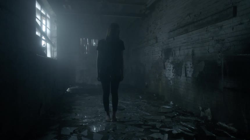 A woman stands on broken glass in an abandoned room